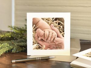 Christmas card of Baby Jesus's hand holding onto a man's finger
