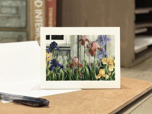 A card with a watercolor of an iris garden alongside a barn