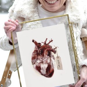 Girl holding art print of the human heart with a tag hanging that reads, "spoken for"